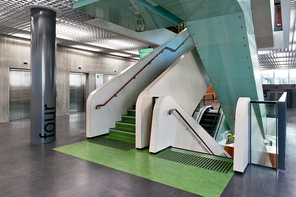 A stair landing between two flights of stairs. There are studs in front of each flight showing that people with impaired vision were taken into account when designing these stairs. 