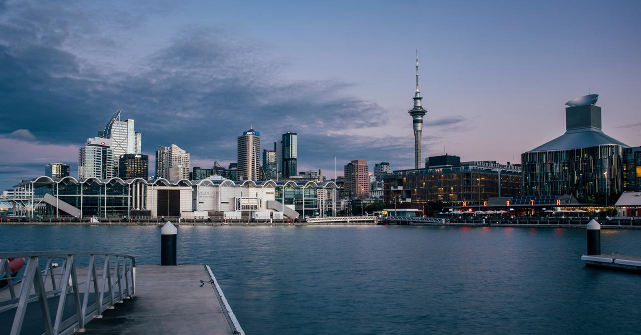 View over the harbour from North Wharf, looking into Auckland city centre, with the Skytower as backdrop, dusk evening light over the water with the Viaducts event centre and ASB waterfront theatre in view