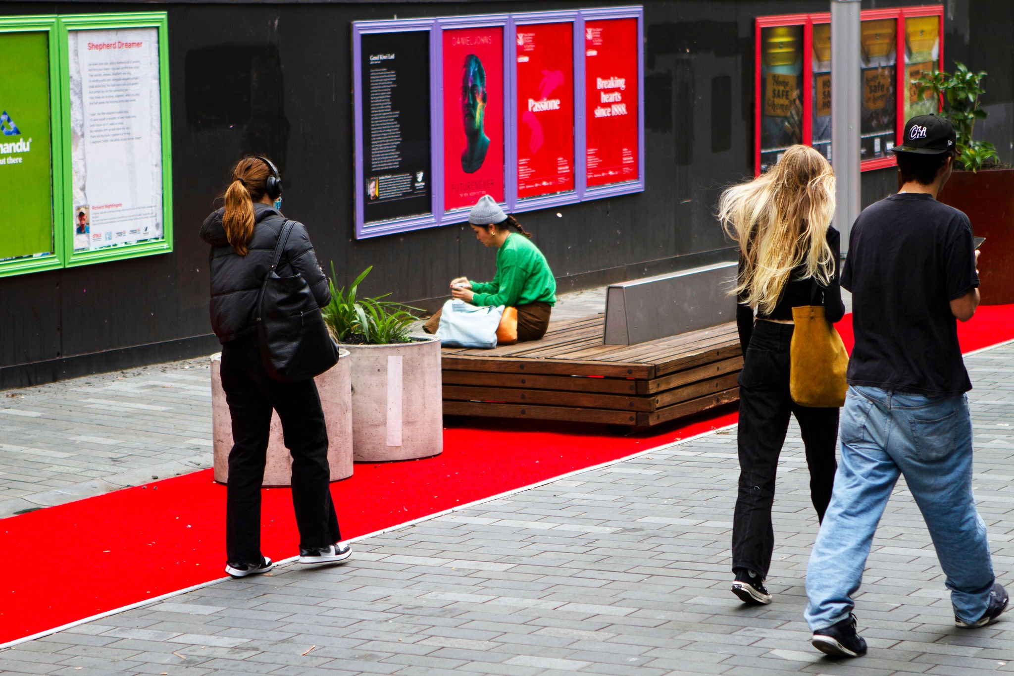 People walking along Lorne St TUI and one sitting on the bench