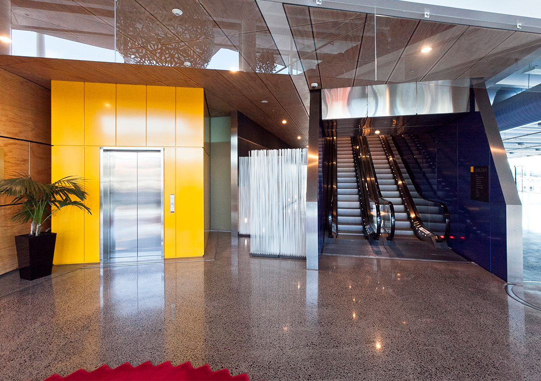 Locating the lift in sightline from the main entrance and providing strong colour contrast assists users in locating the lift. Co-locating vertical circulation provides users with choice. Stairs should not be the only means of accessing part of a building. This is not only for people with temporary or permanent mobility impairment, but also for people carrying boxes, using trolleys, or moving furniture.