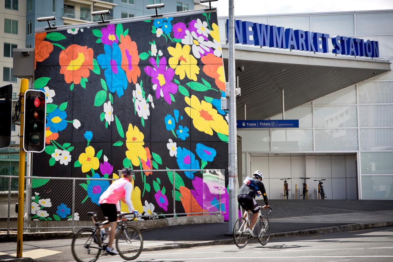 2 Cyclist biking past the murial of Newmarket train station entrance