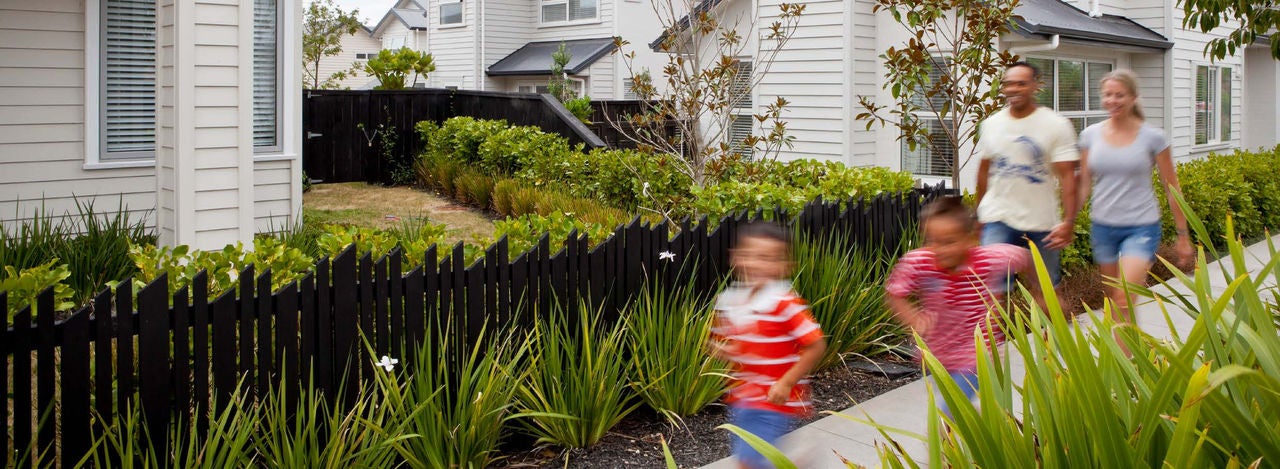 2 adults walking and 2 kids happily running down a suburban st