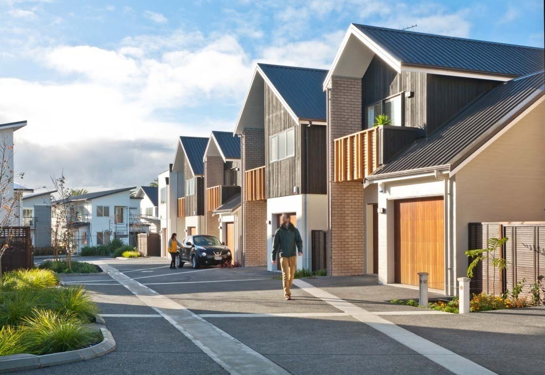 Looking down Buckley Avenue at the six two-storey terraced houses sitting next to a shared lane. The lane is concrete with attractive lines serving as gutters. There are garden beds softening the boundary between the lane and the homes. 